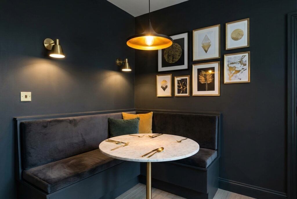 Dark charcoal painted dining corner with brass fixtures creating intimate restaurant ambiance